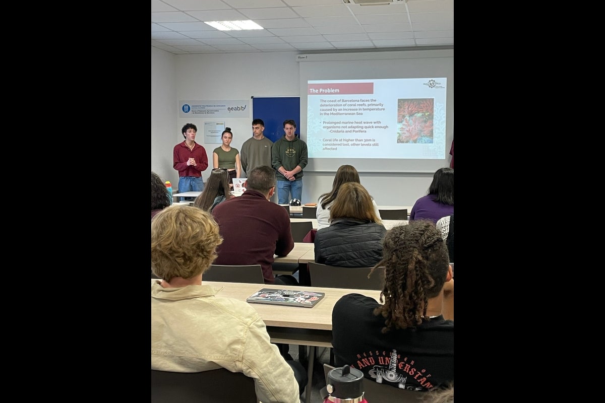 A group of students presents in front of a projector screen 