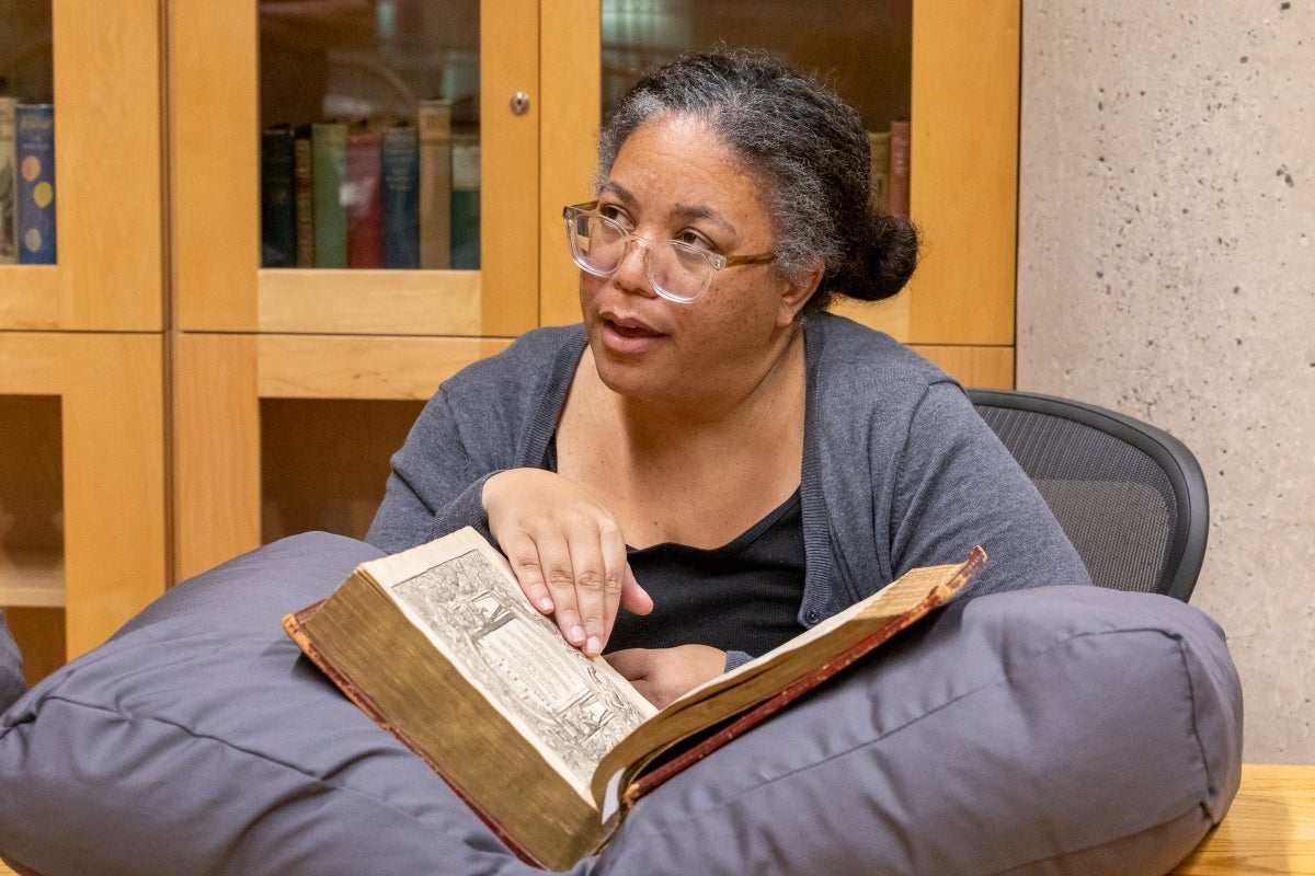 ASU professor Brandi Adams looking at book with John Milton's handwriting