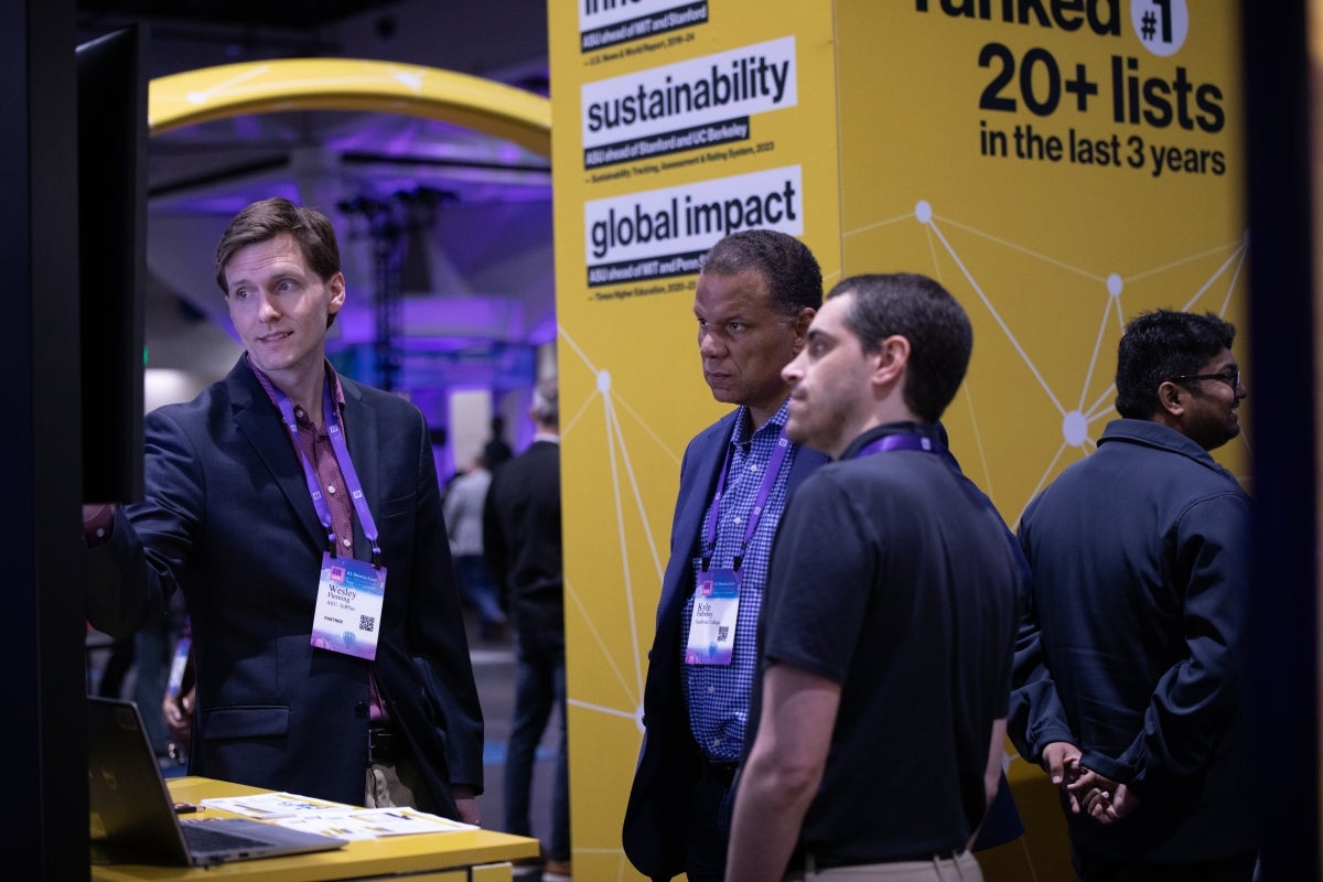 People interacting with ASU exhibit on convention floor