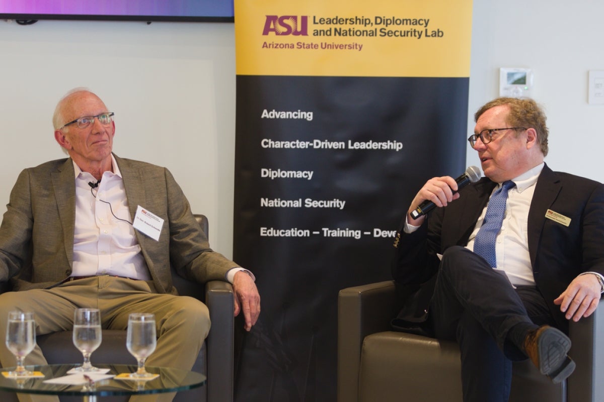 Ambassador David Scheffer talks at a panel discussion, with Robert Schmidle listening