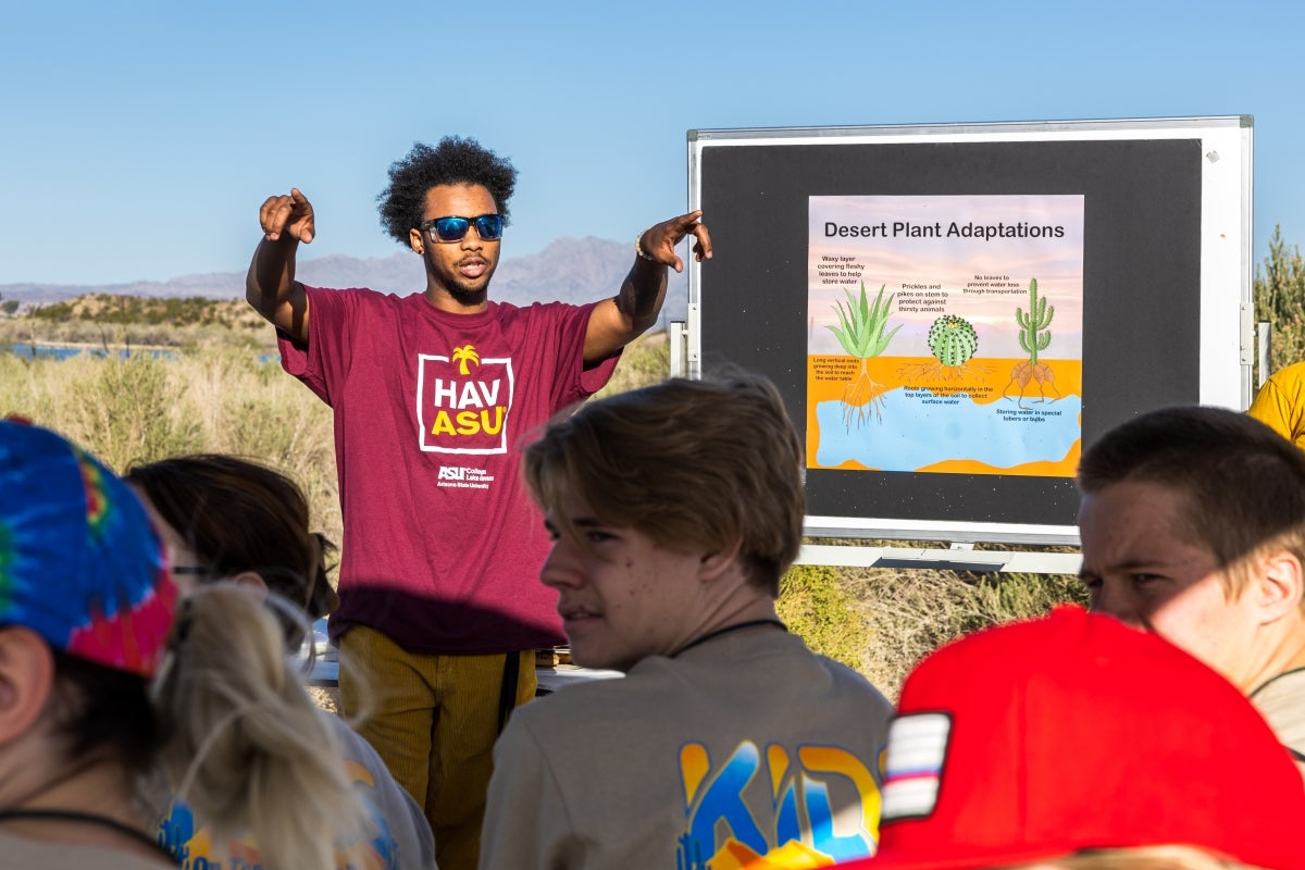 A man wearing an ASU shirt stands in front of a group of kids