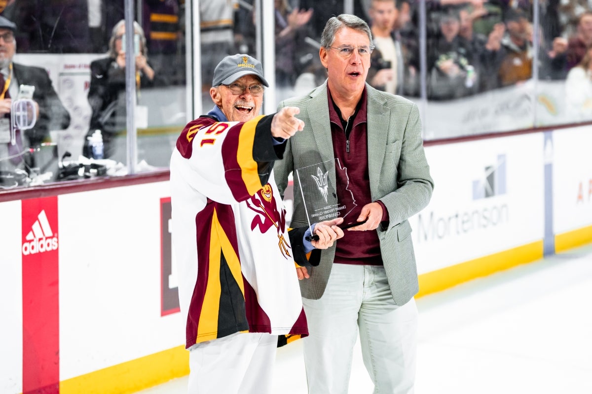 Don Mullett stands excitedly next to Morgan Olsen on the ice rink of the Mullett Arena