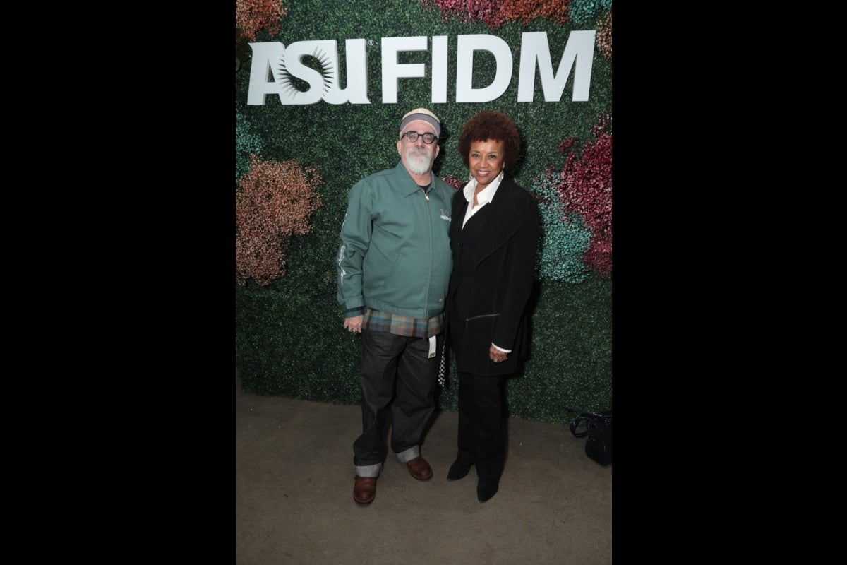 Two people posing in front of a sign that says 