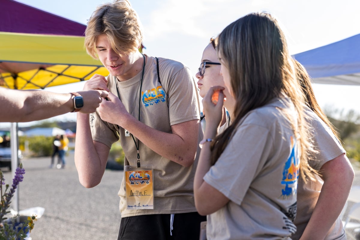 A group of students gather to look at something close up that someone is holding