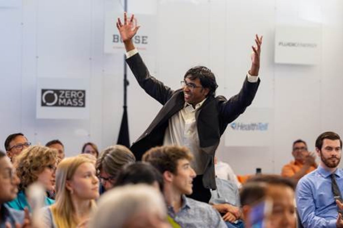 Man standing up from audience with arms in air