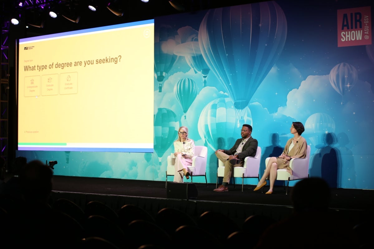 Three people sitting on stage for panel and presentation