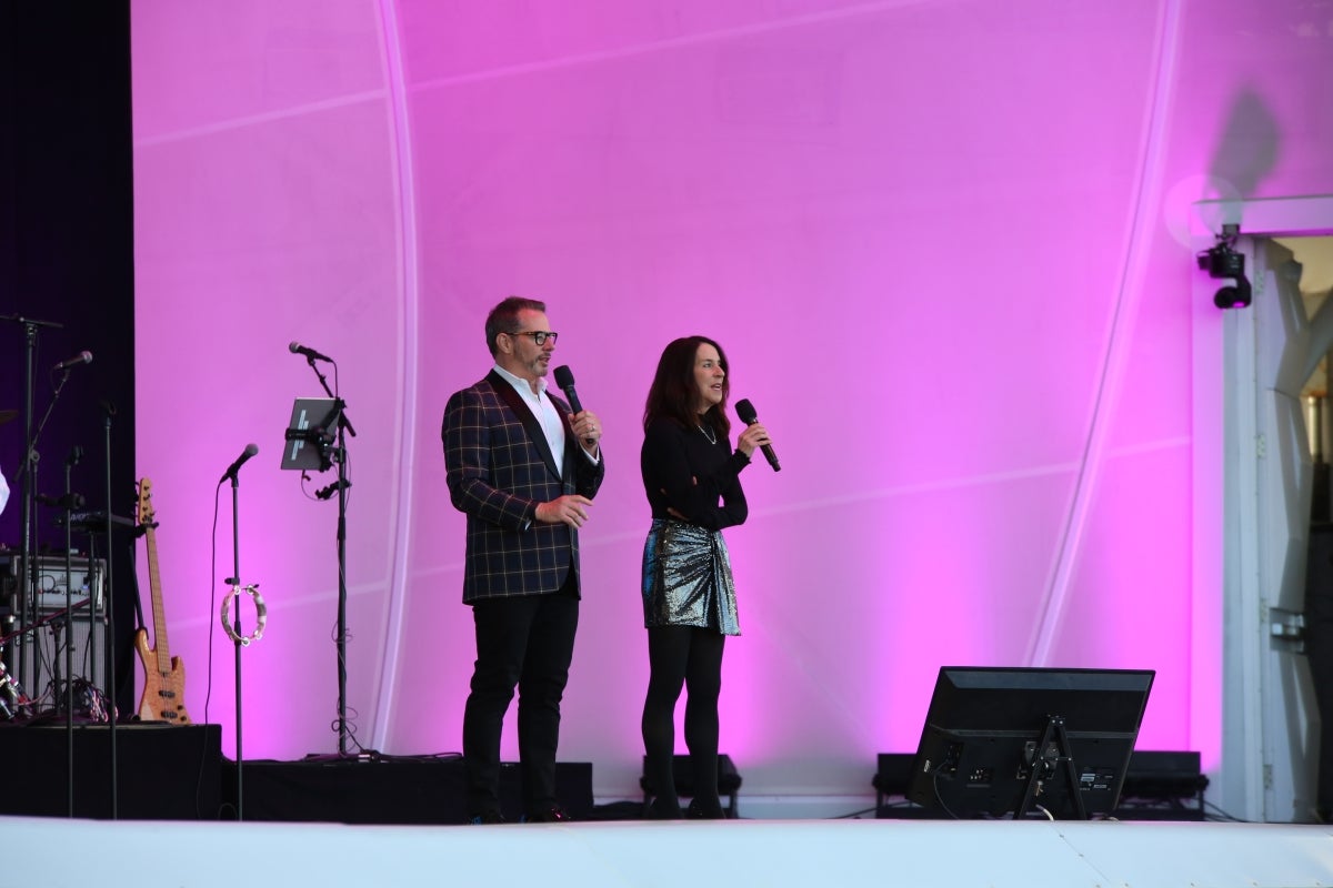 Two people standing on stage talking into microphones