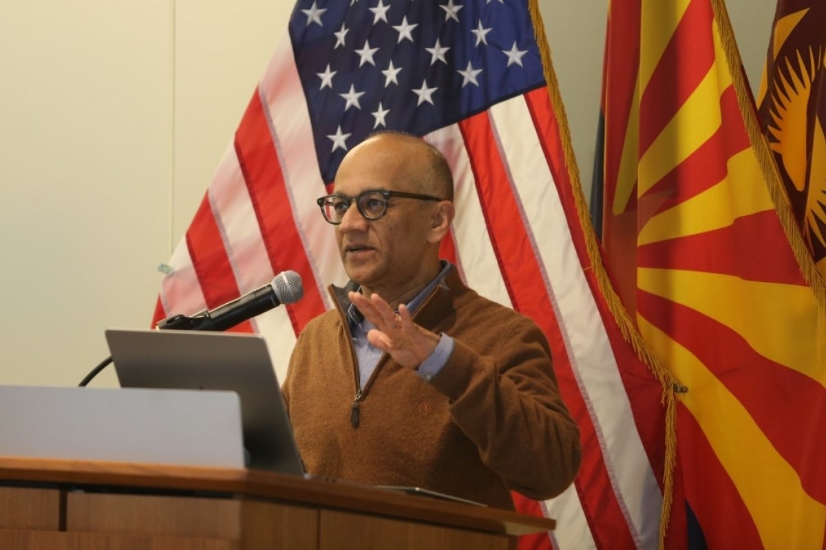 Mahmud Farooque presents to an unseen audience behind a podium