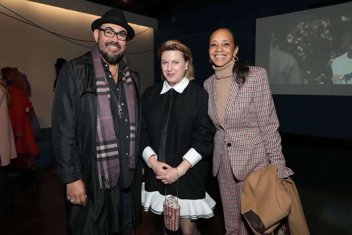 Three people smile for a group photo at a museum event.