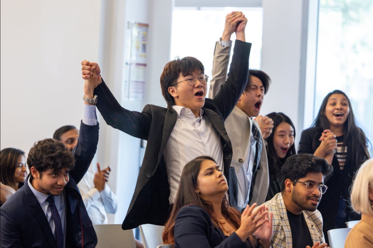 Several young adults grab hands and jump for joy in a crowd