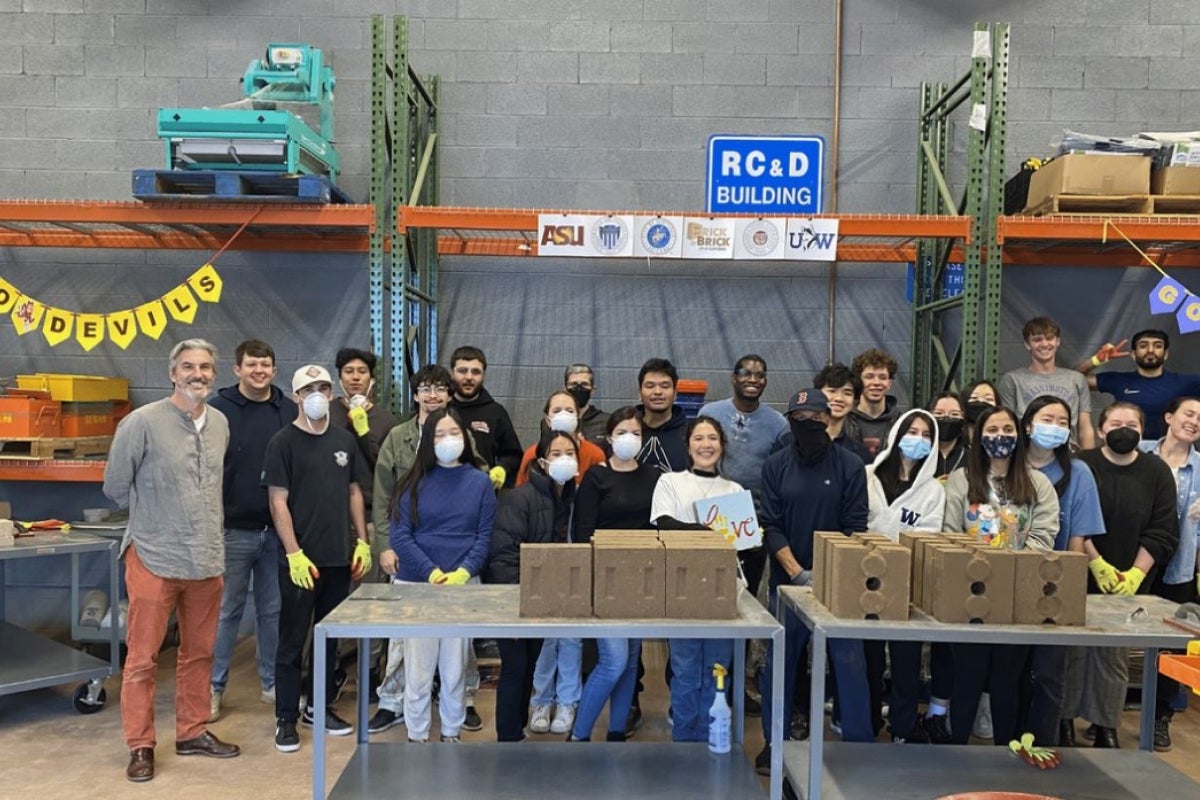 A group of young people stands in front of a table full of blocks