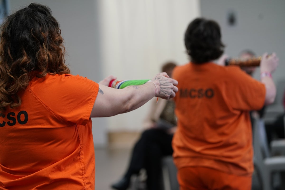 Incarcerated women shake handcrafted music shakers to create a unified beat. Each woman calls out a word: Peace, hope, purpose.