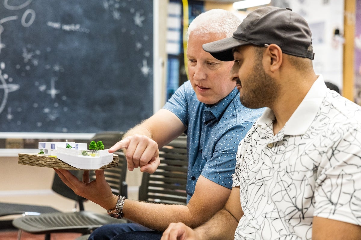 Two men look at a small model of an architcture design