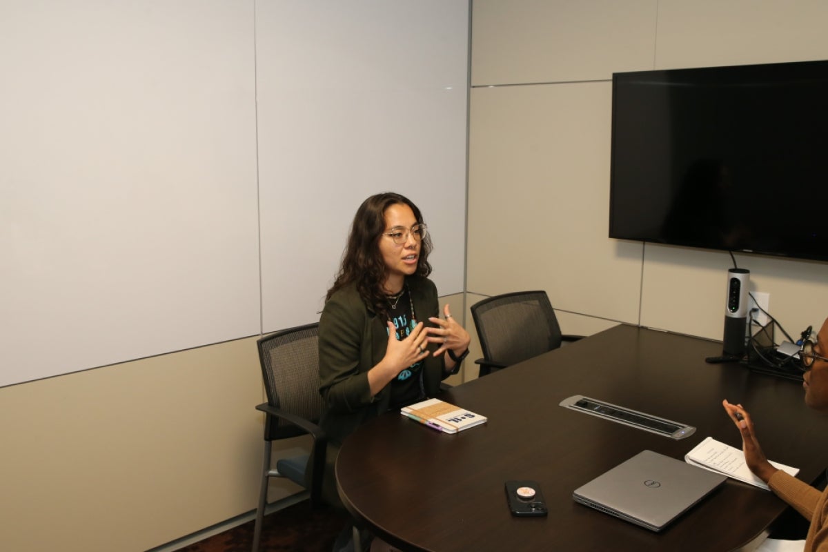 Kayna Mendoza sitting across a table from someone mid-conversation