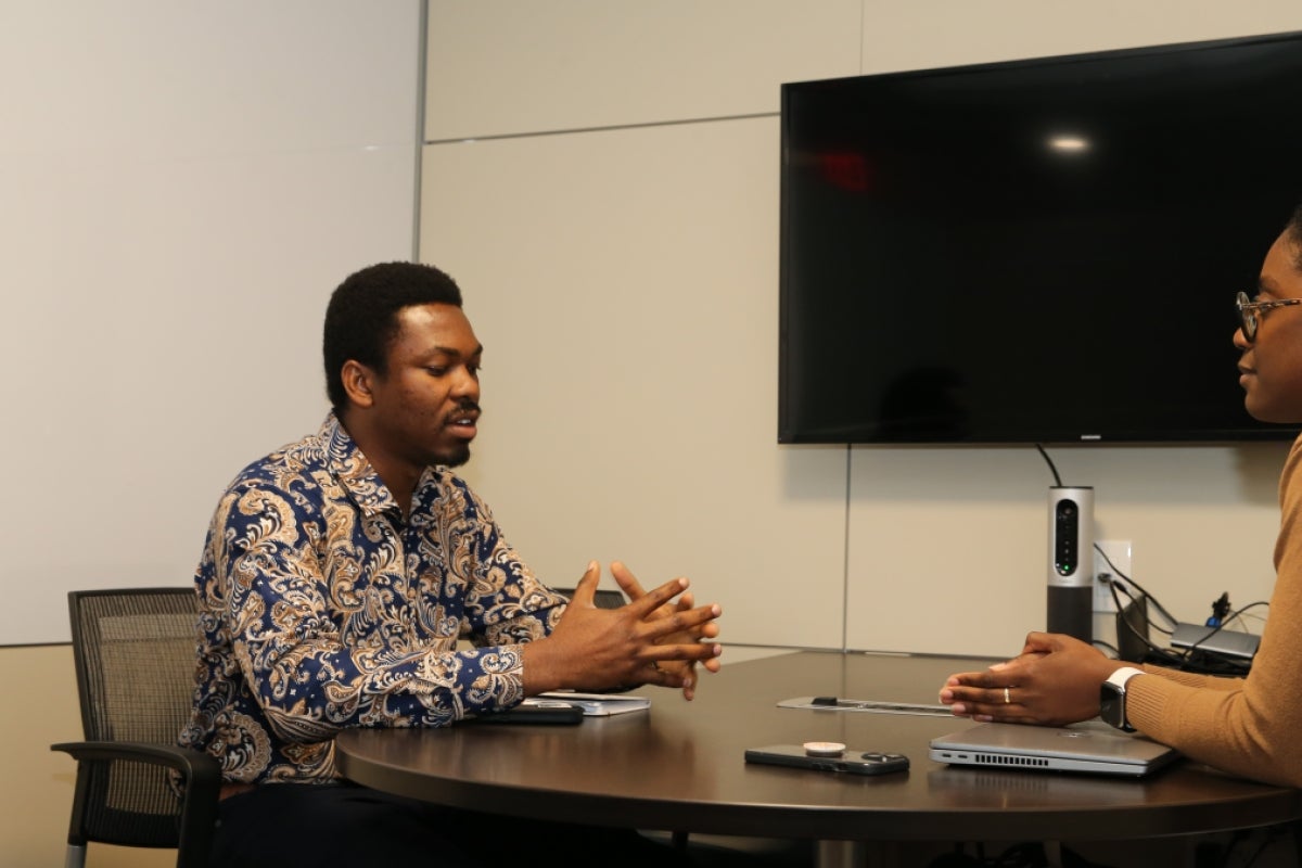 Jide Olugbade sits at a table across from a person