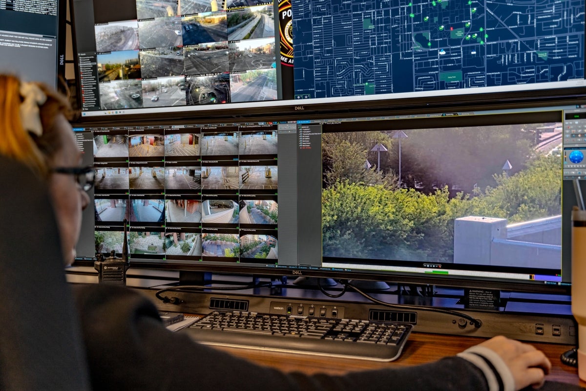 Woman seated at a desk in front of multiple monitors.