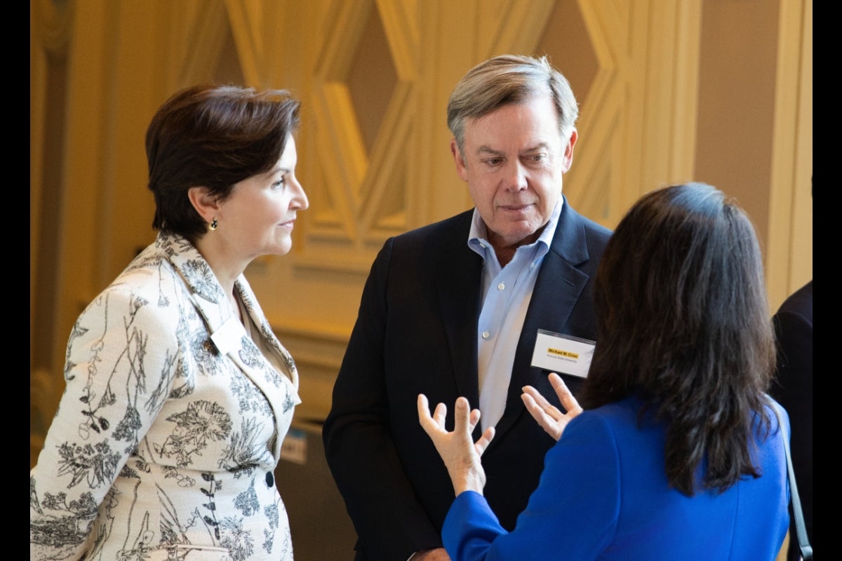 Three people talk and mingle at event