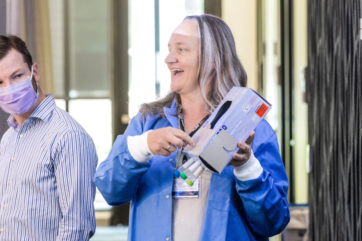 Woman holding box with medical vials sticking out of it