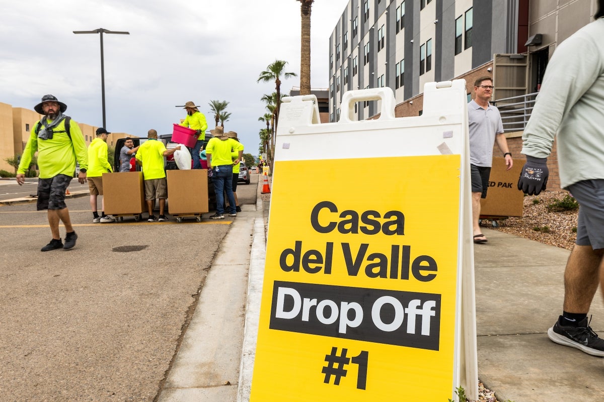 Sign that says Casa del Valle drop off with movers pushing boxes in the background