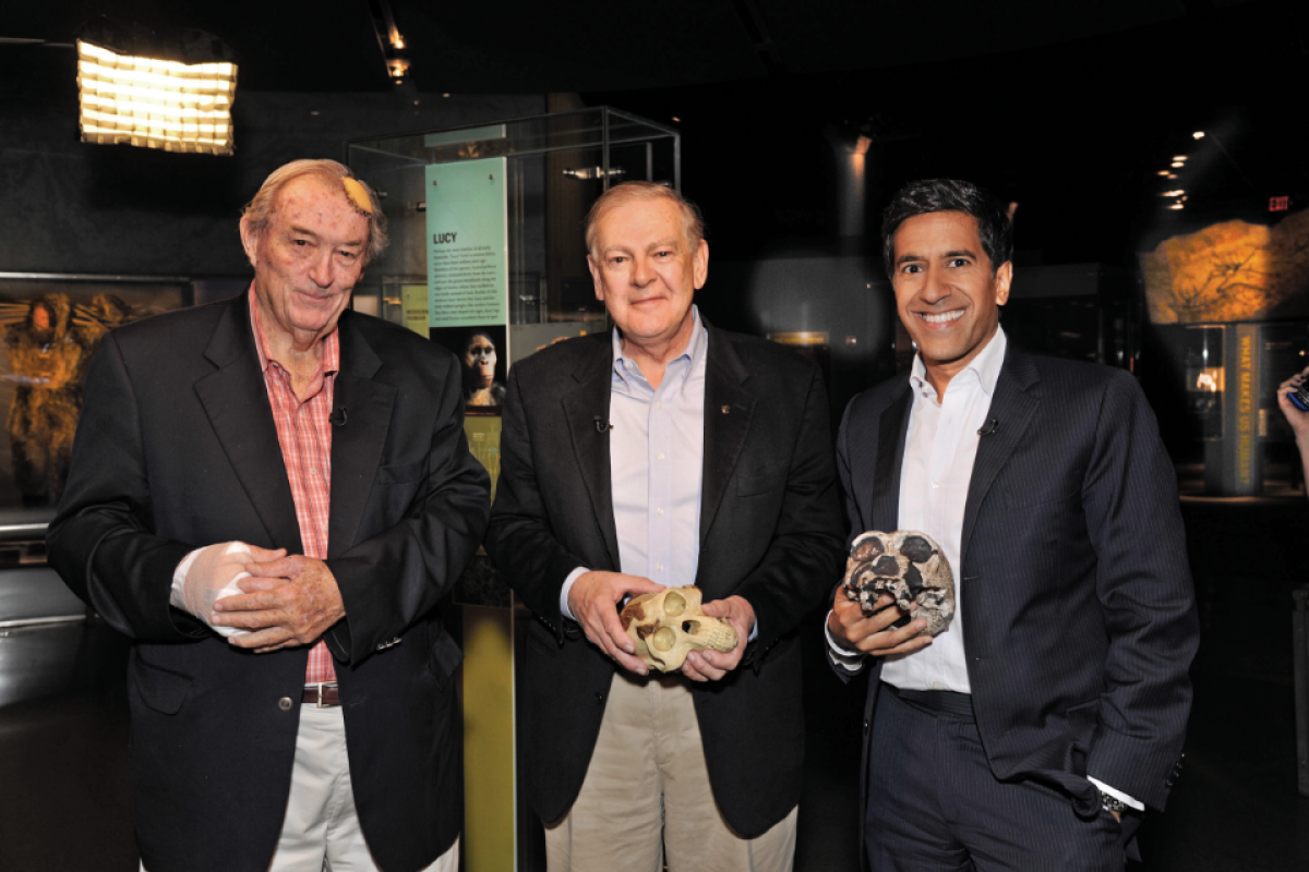 Three men in dark blazers pose for photo after panel event