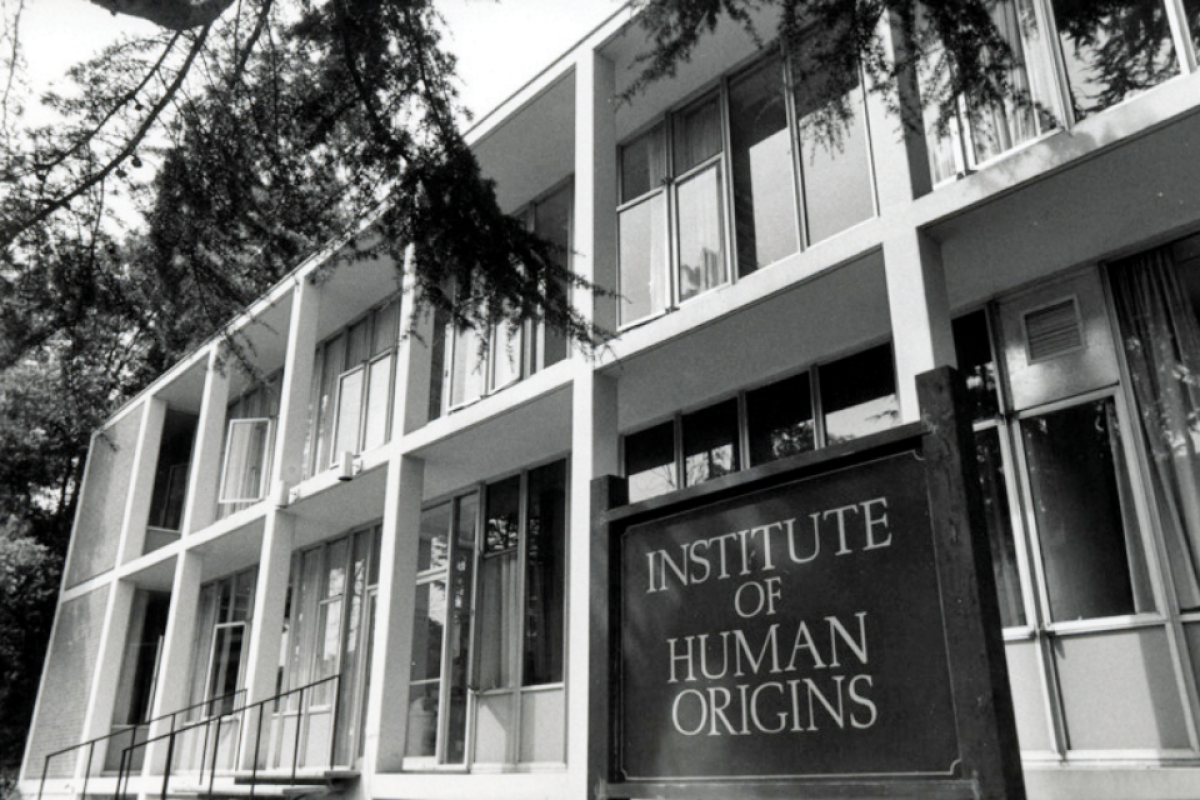 Black and white photo of an academic building with a sign in front hat says Institute of Human Origins