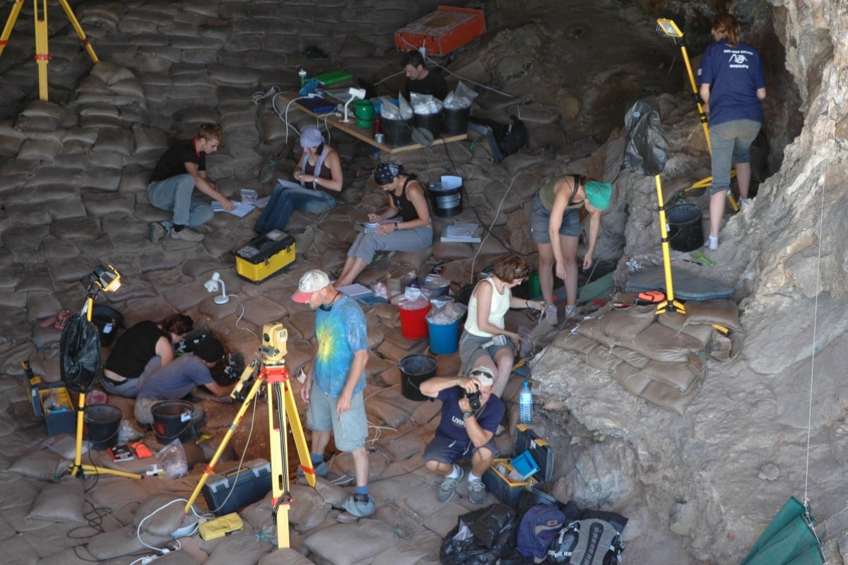 A group of people using various equipment and tools work in a cave