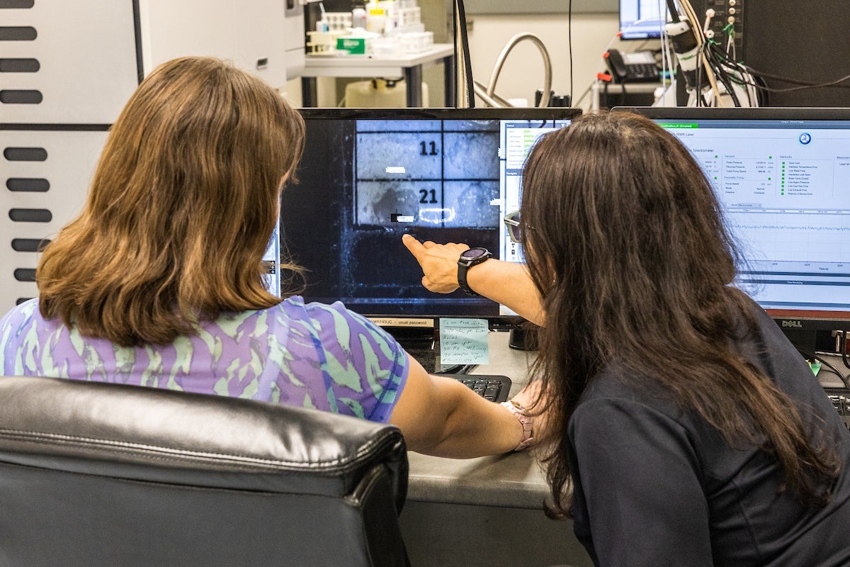 ASU Professor Shirly Montero at a table looking at a computer screen with a student.