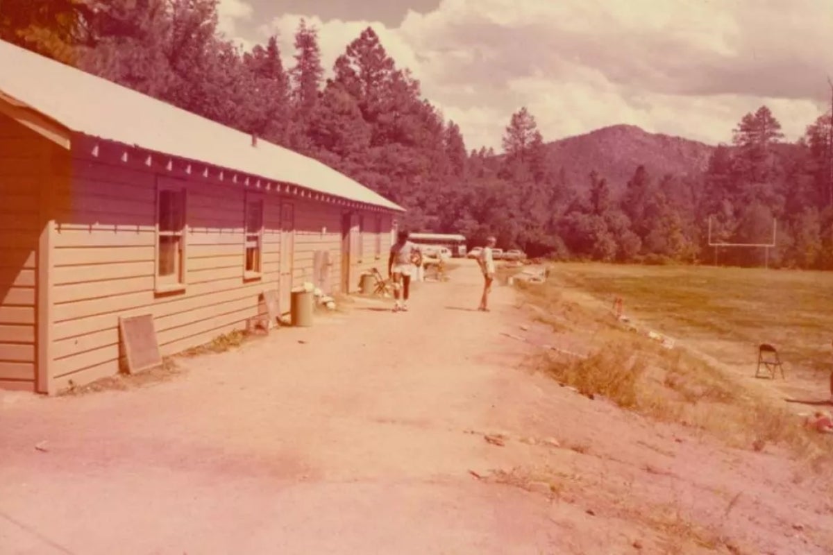 Old photo of cabins and a football practice field in the woods