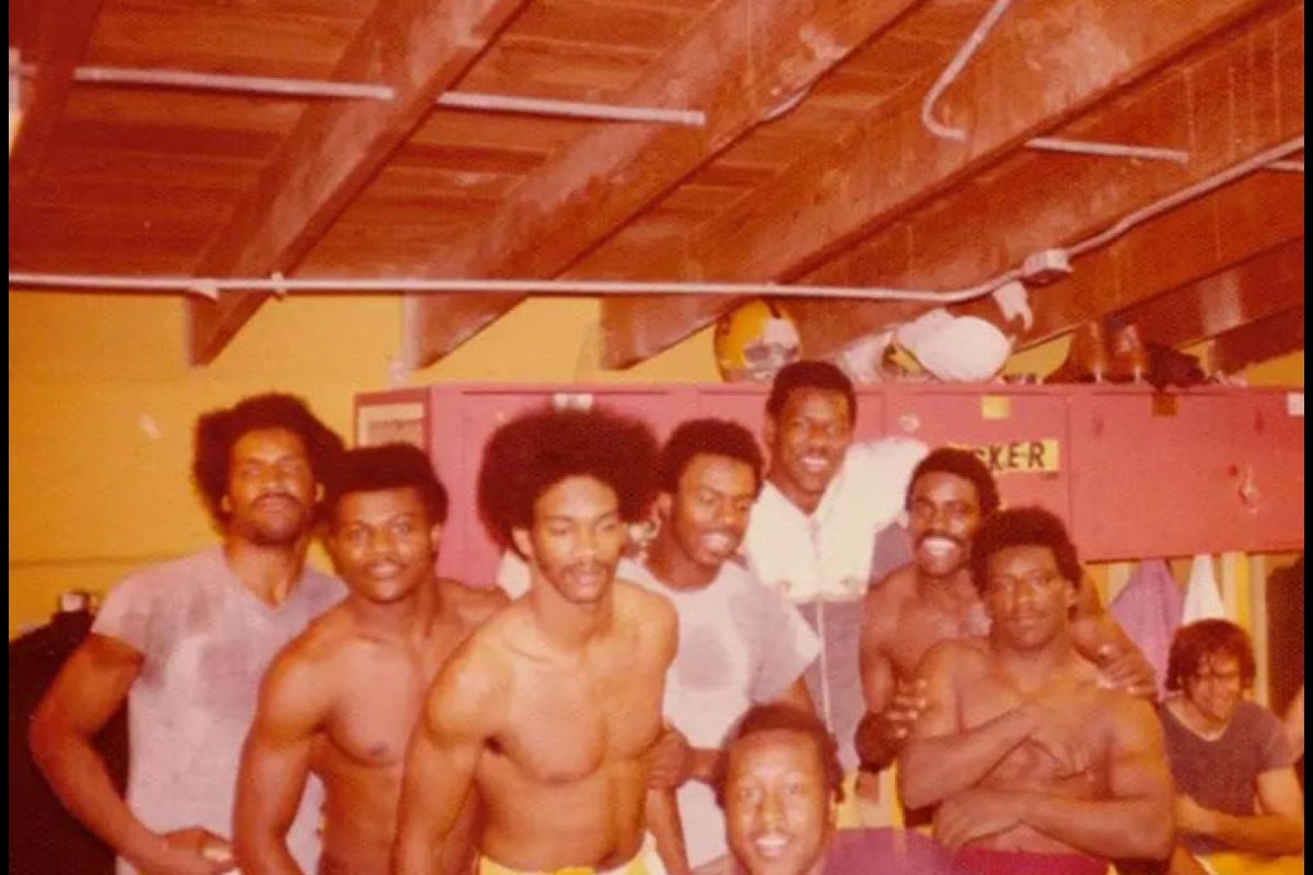 Former ASU football players pose for a photo in a locker room cabin