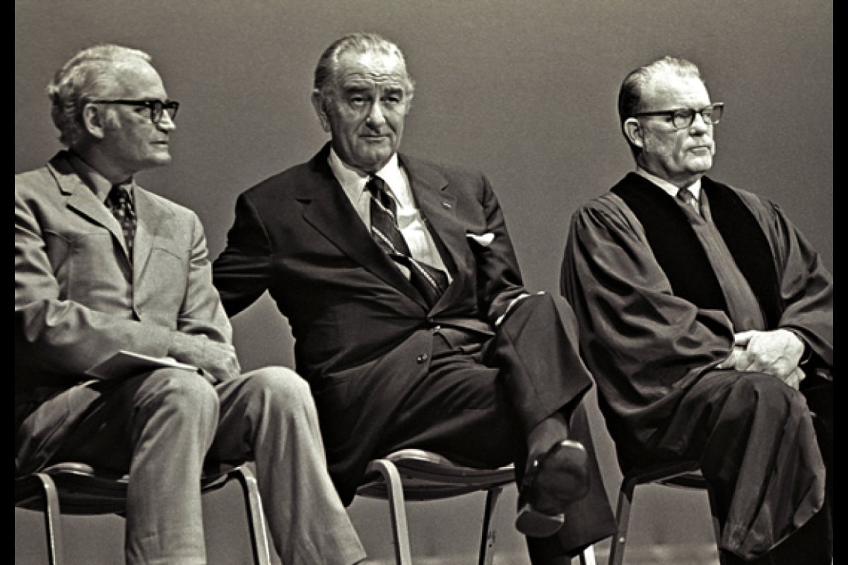 3 men sit on a stage