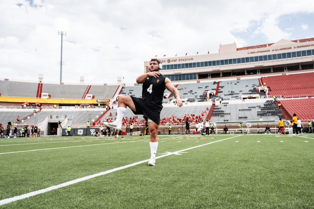 An ASU football player stretches and works out on a stadium field