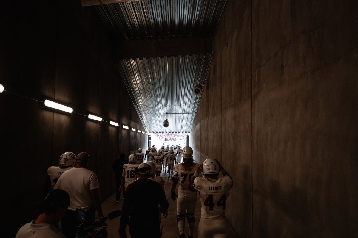 ASU football players walk through a tunnel toward a field