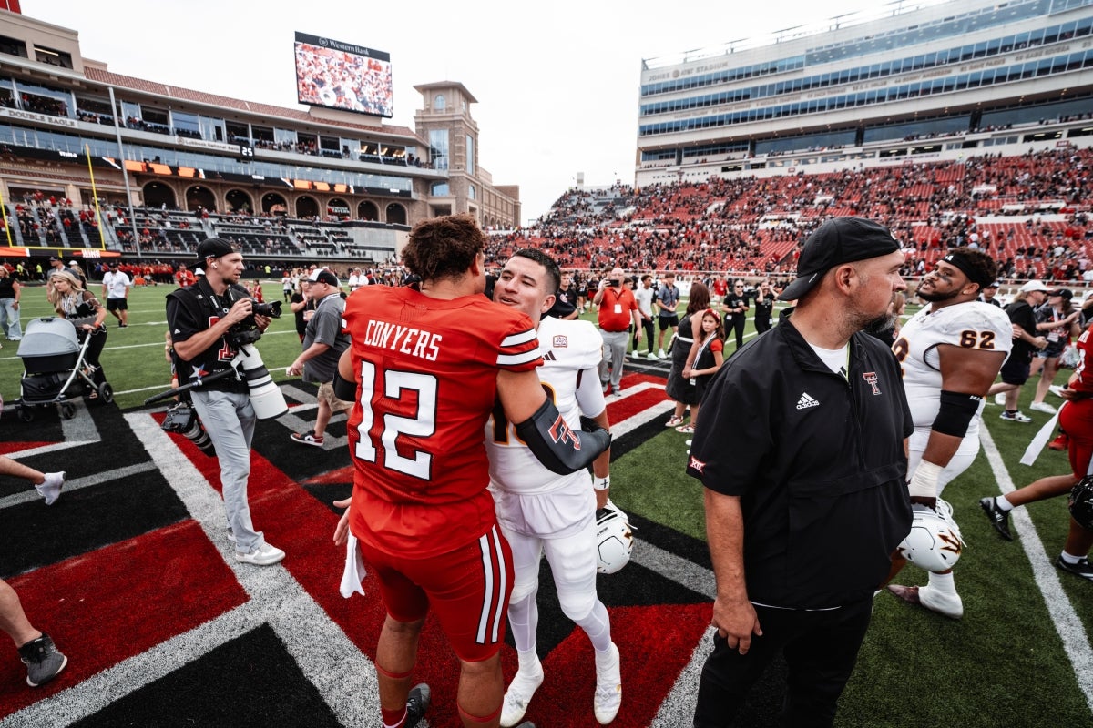 Apposing football team players embrace on field after game