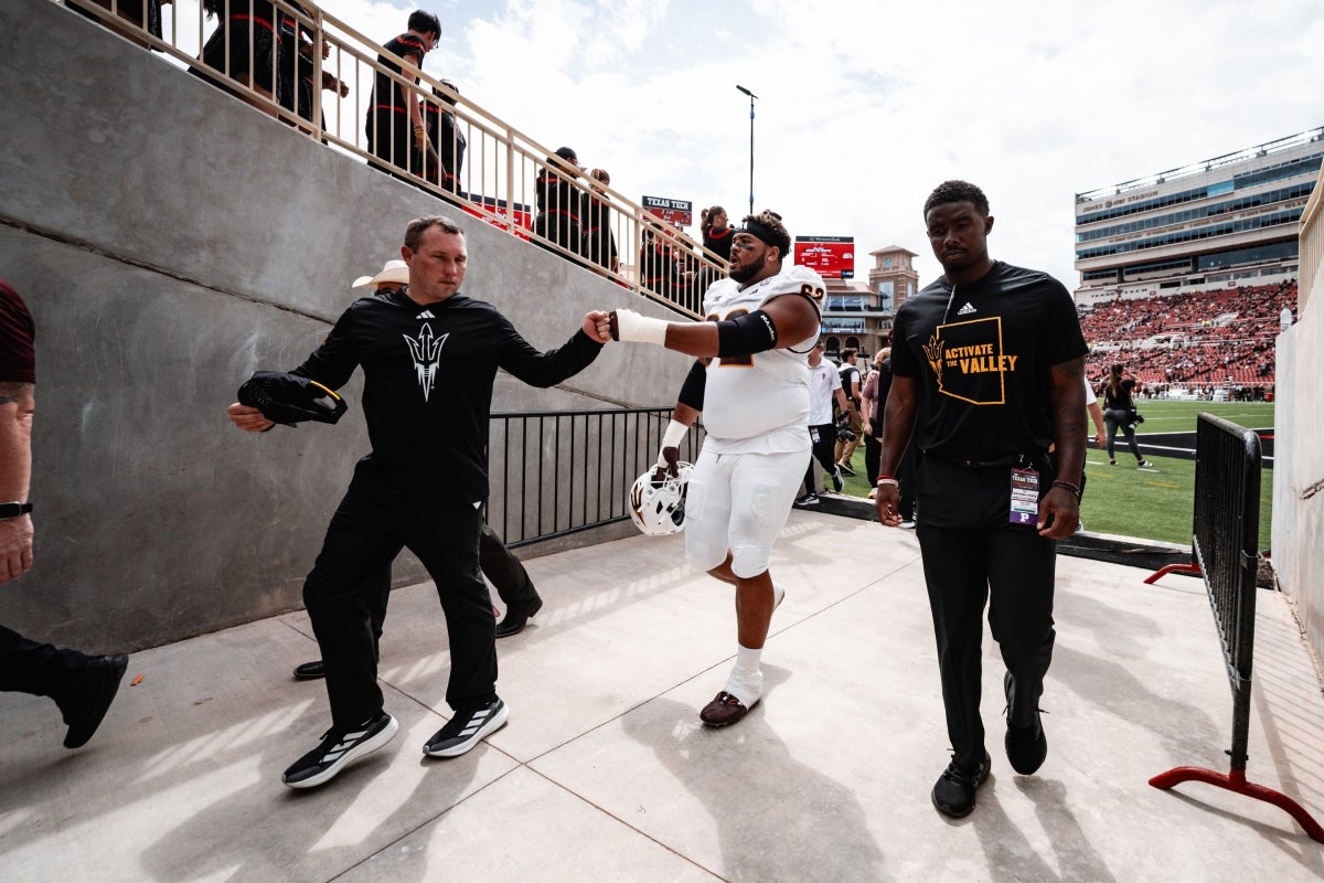 Coach and football player fist bump in tunnel on side of football field