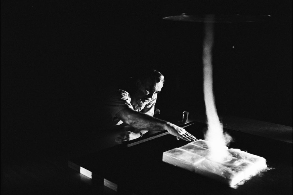 Black-and-white photo of a man reaching his hand toward dry ice.