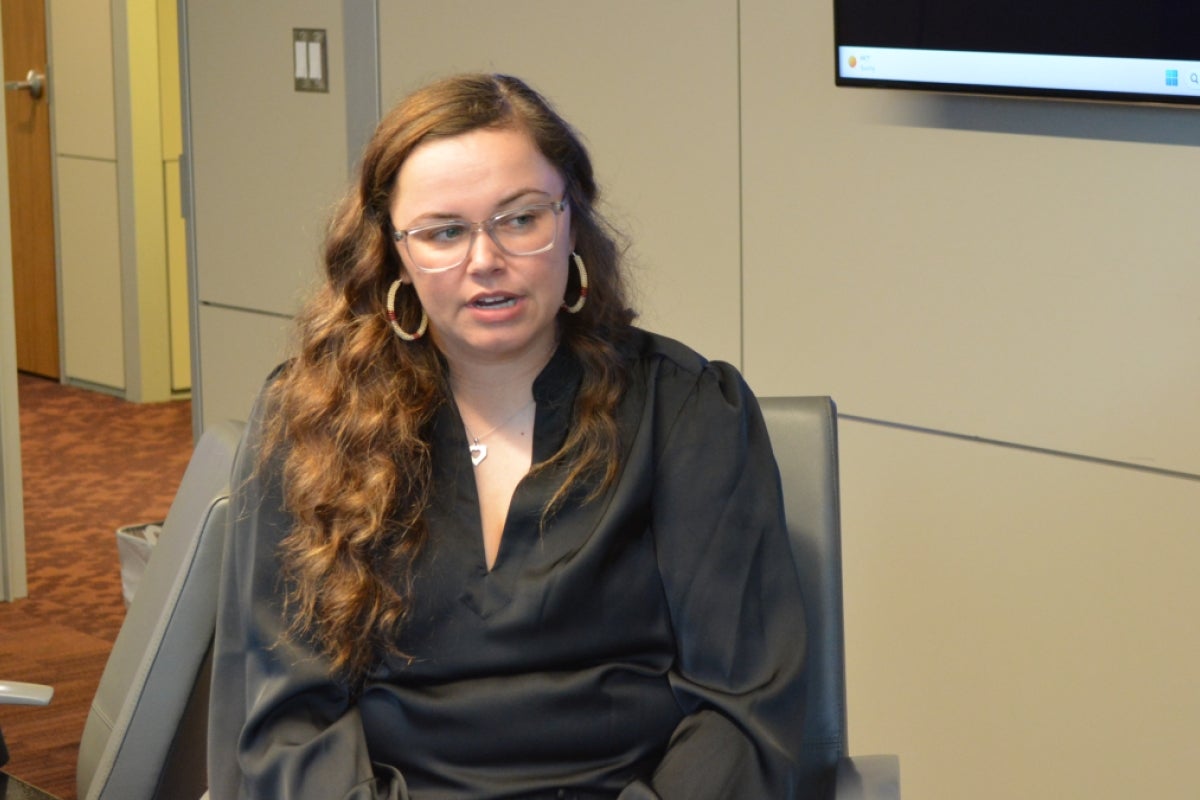 Mikaela Bledsoe Downes, a young woman with brown hair, wearing a black blouse and earrings