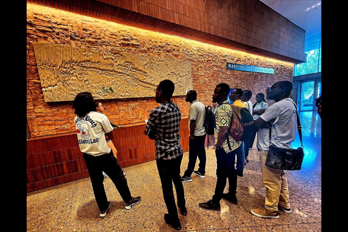 CARISCA team members observe a large topographical map on a wall.