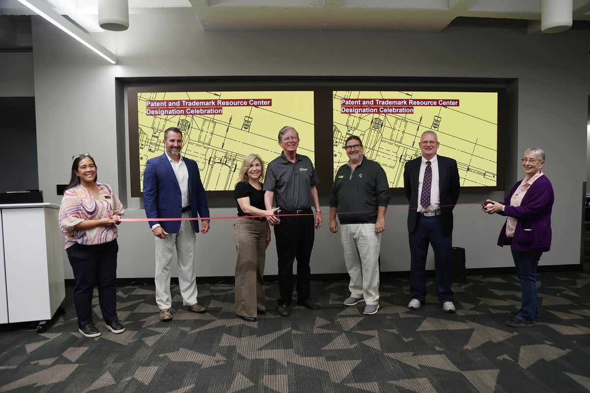 A group of people standing posed for the camera for a ceremonial ribbon-cutting.