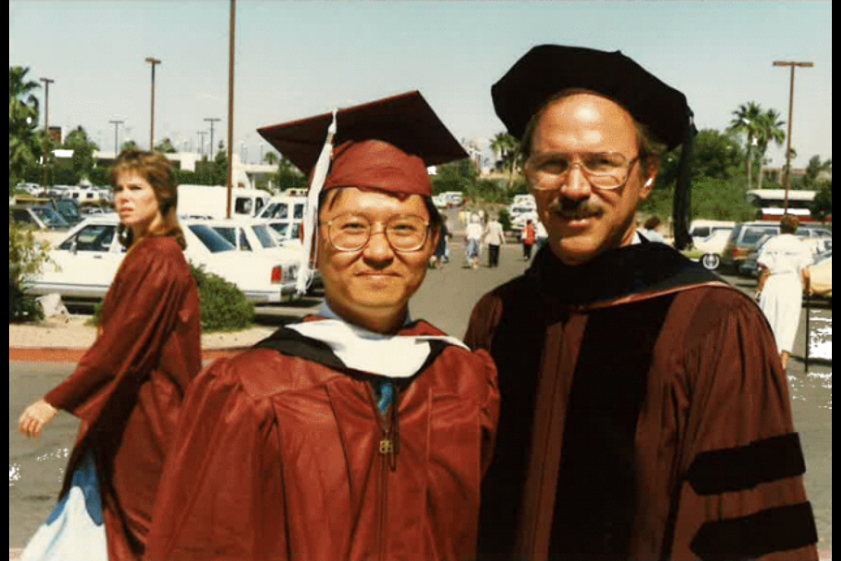 Two men wearing maroon graduation regalia.