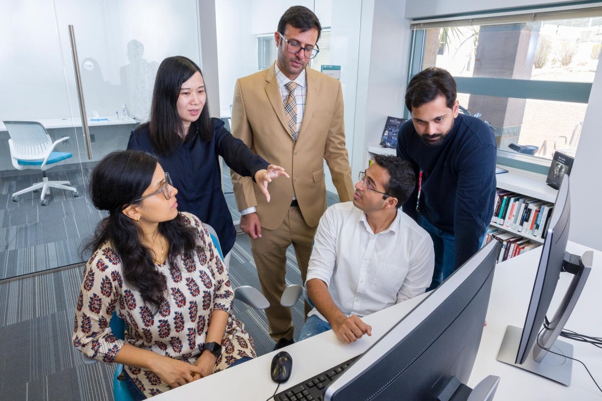 People grouped together around a computer screen.