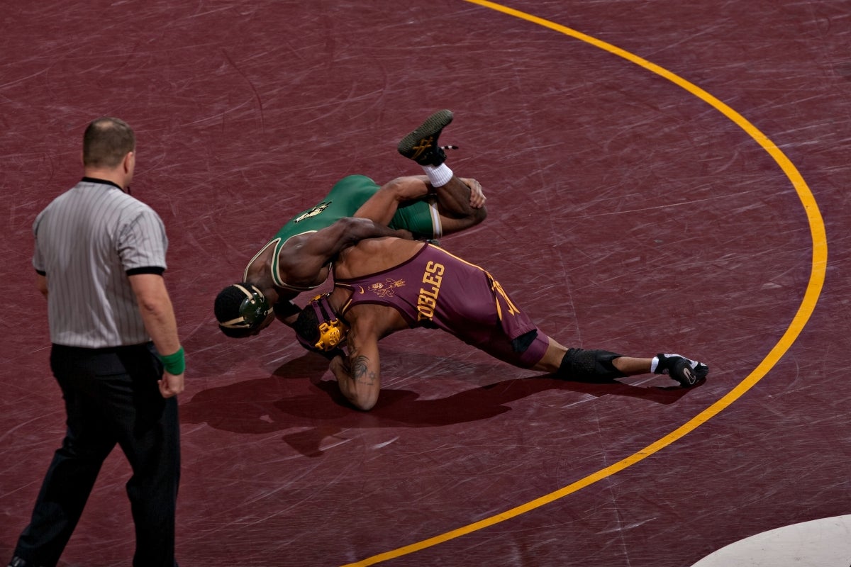 Two men wrestling on maroon mat