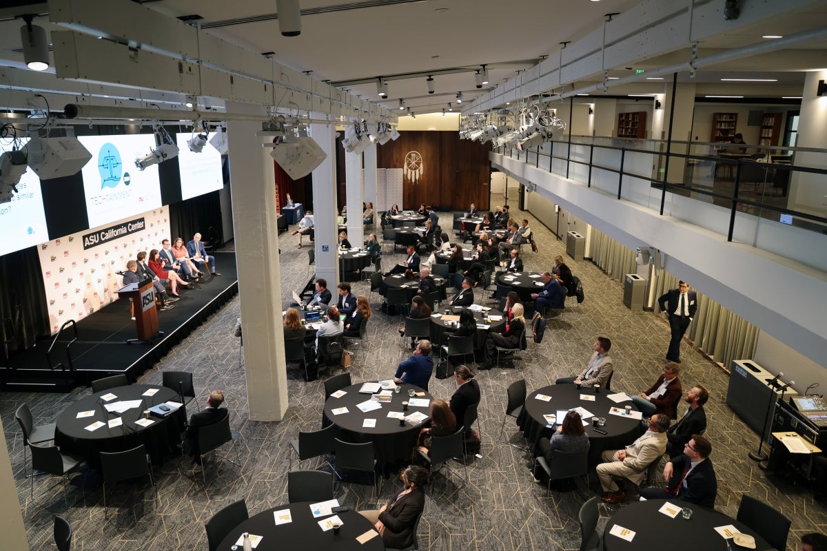 People sitting at groups of round tables watching panel