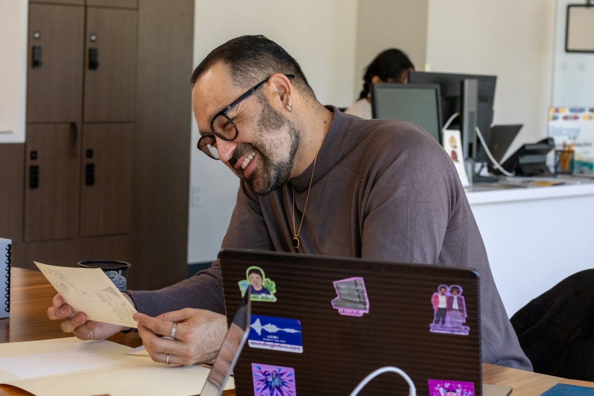 Francisco Carrillo smiling while looking at an artifact. 