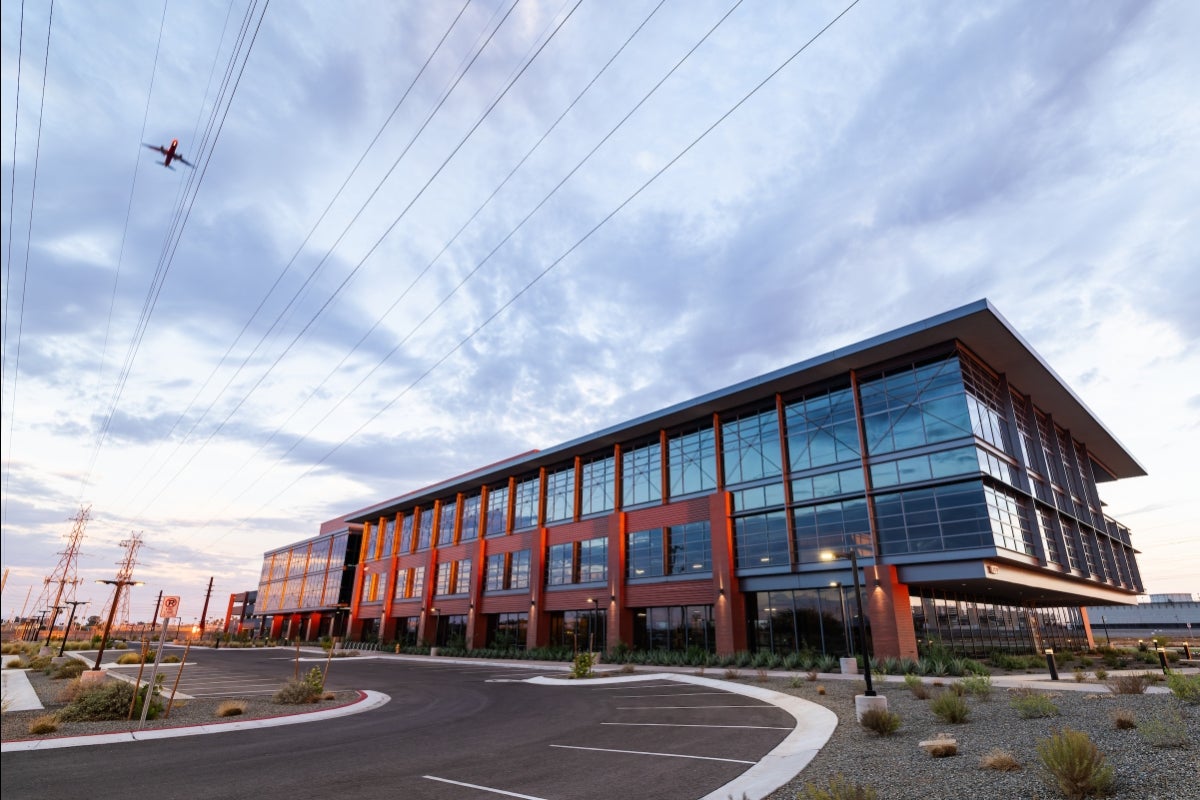 An exterior shot of a building, with a plane flying overhead