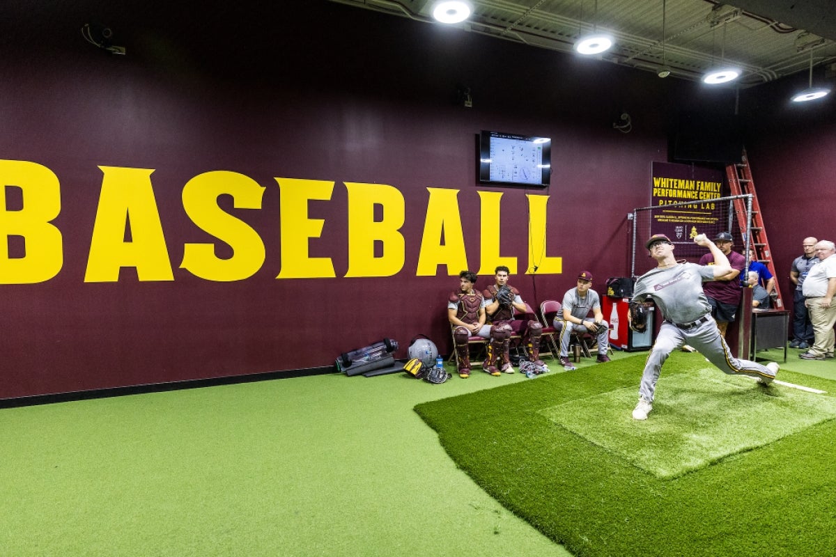 A pitcher throws a pitch in an indoor bullpen