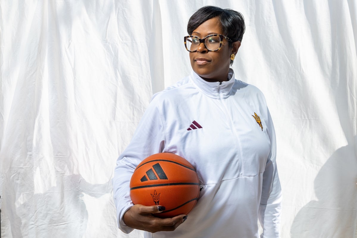 ASU women’s basketball coach Natasha Adair holds a basketball as she poses for a portrait in front of a white background 