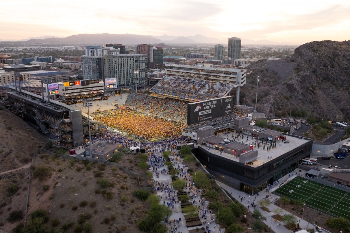 A drone photo taken above a football stadium showing a crowd of ASU fans wearing gold swarming the field