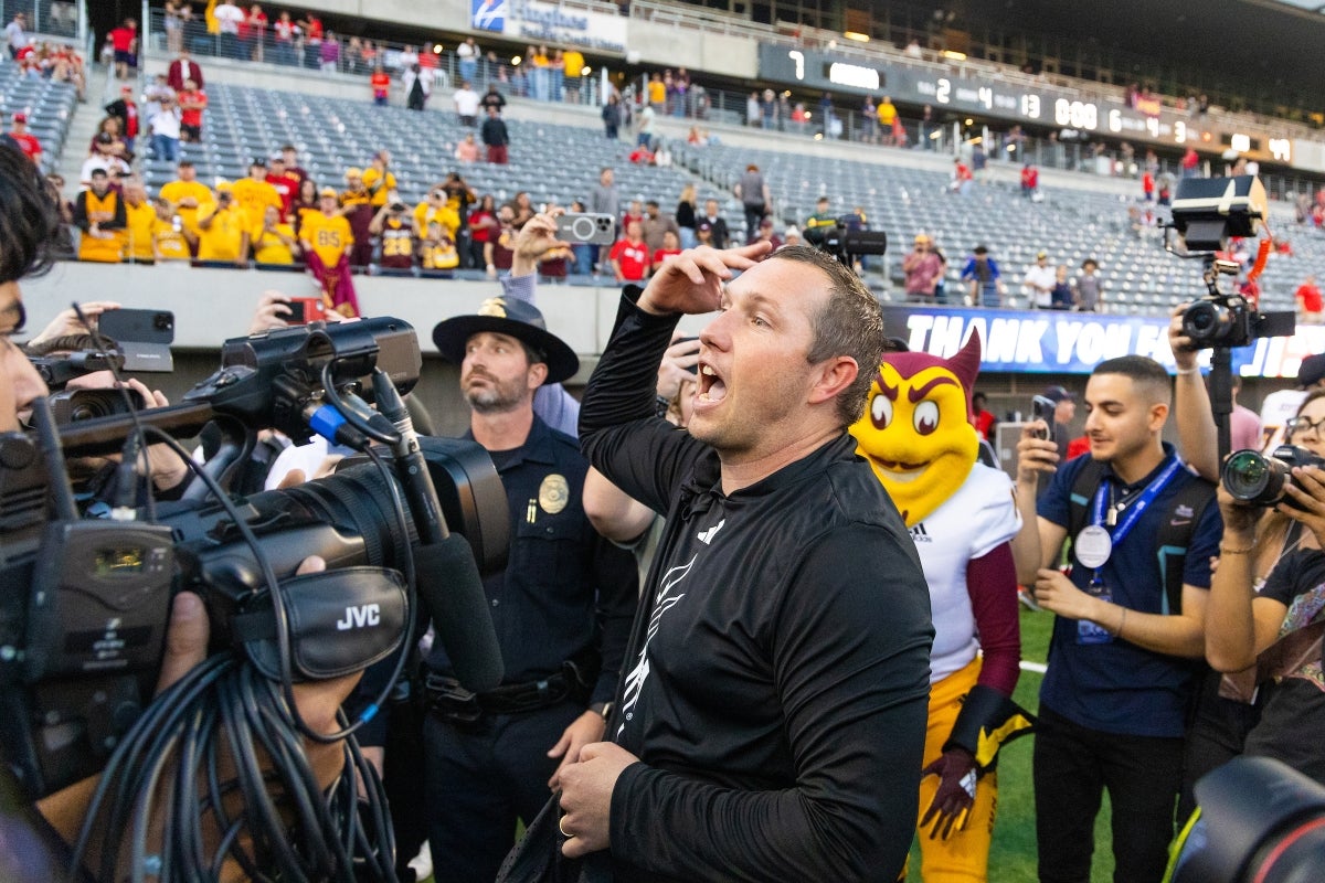 Camera crew focuses on ASU football coach on field after game