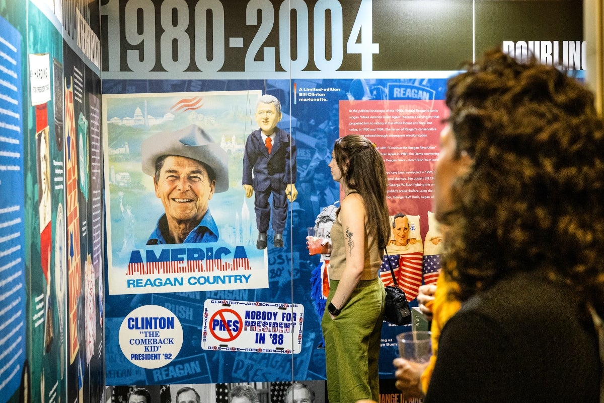 People looking at a wall display of Reagan-era campaign propaganda