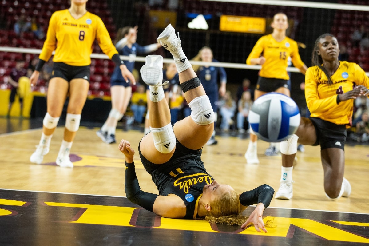 A volleyball player goes head over heels on a court floor